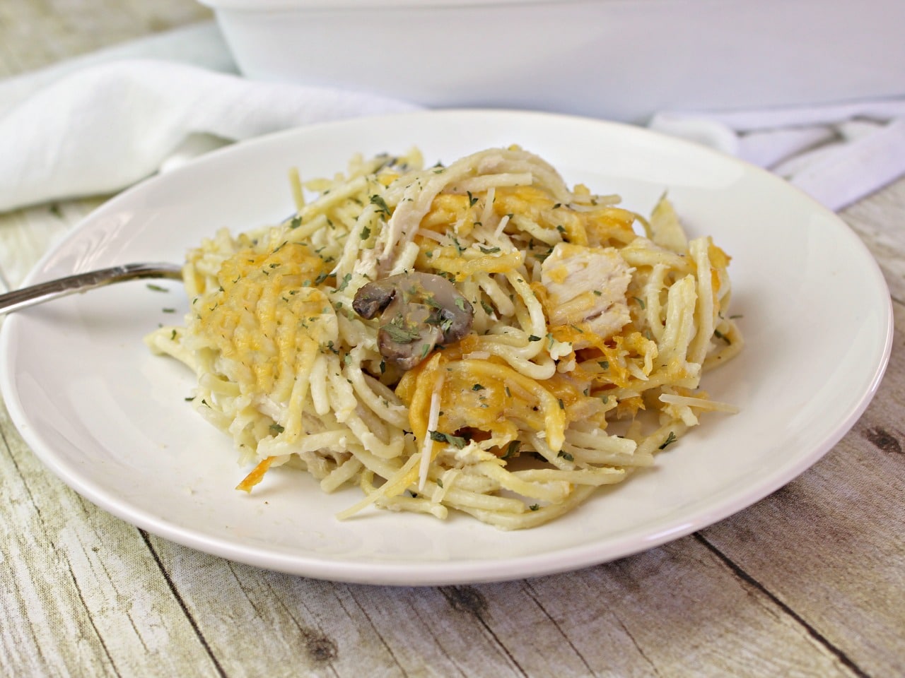 a single serving of chicken tetrazzini on a white place with fork 