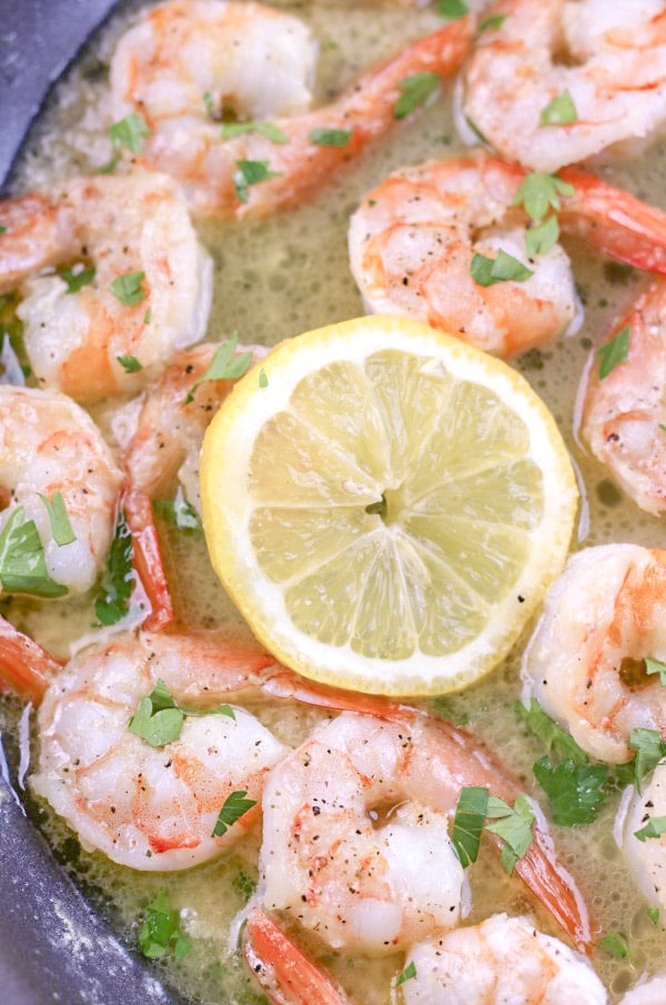 Garlic Butter Shrimp shown in skillet with garlic butter sauce and a lemon slice 