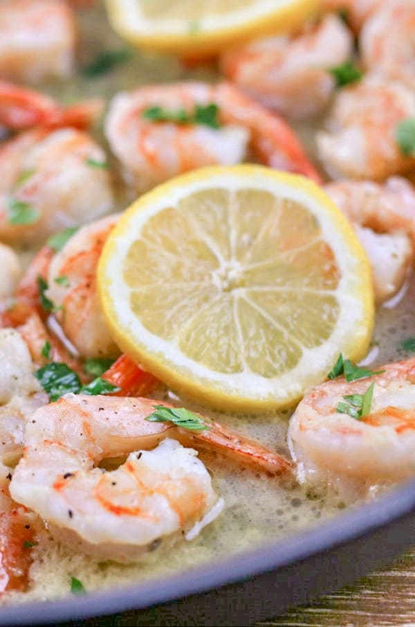 Garlic Butter Shrimp in skillet with garlic butter sauce and lemon slices garnished with parsley. 