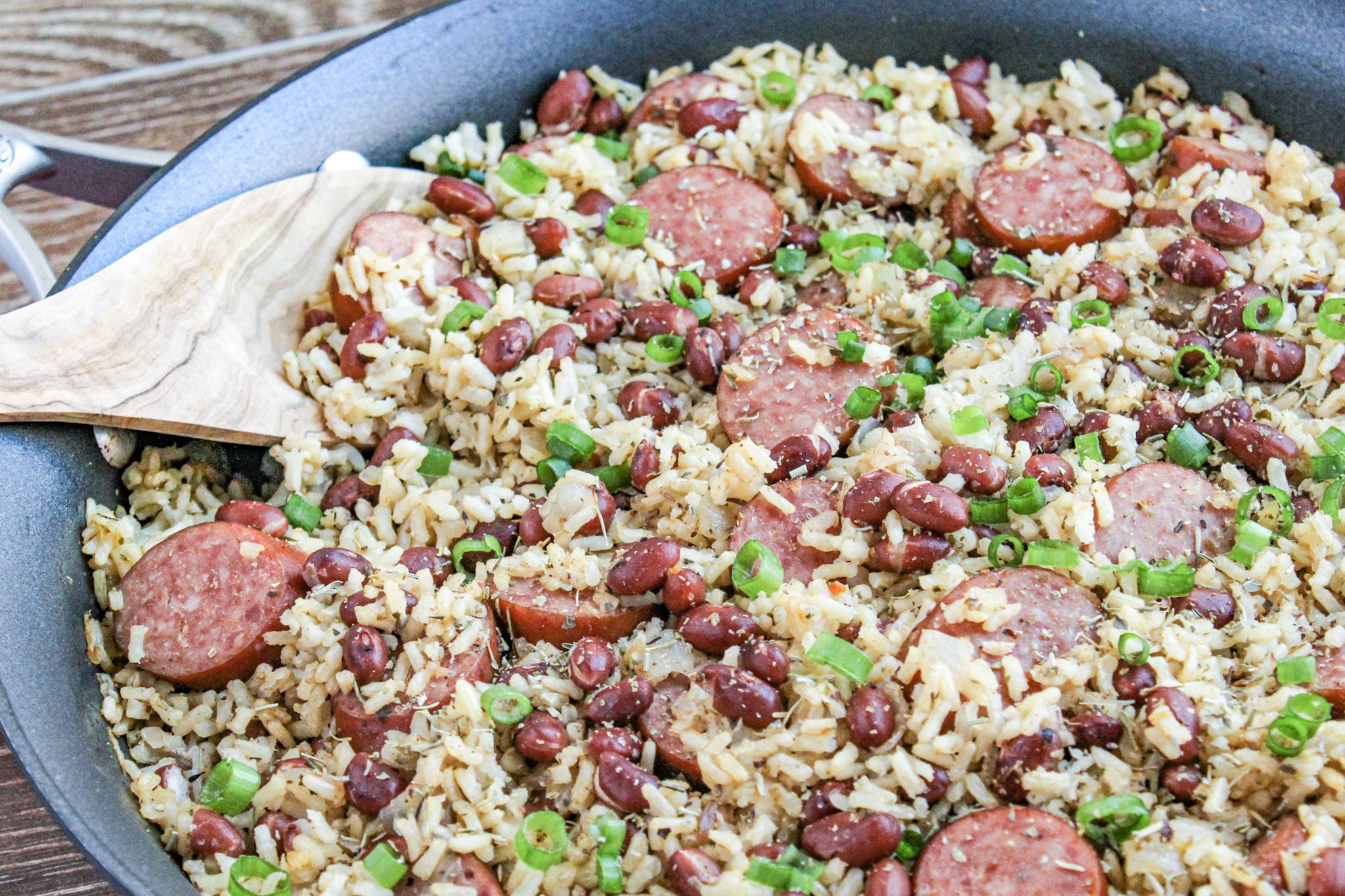 close up photo of red beans and rice in a skillet with wooden spoon and wooden background 