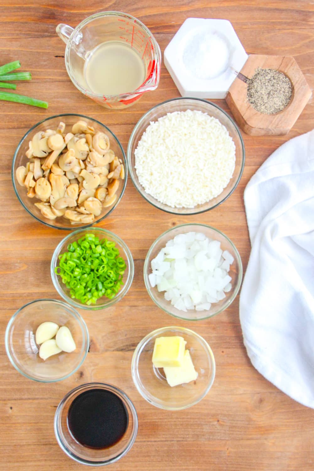 Measured ingredients needed for make Mushroom Fried Rice presented in clear bowls on a wood background.