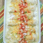 White Chicken Enchiladas in sour cream sauce in white baking dish with handles.