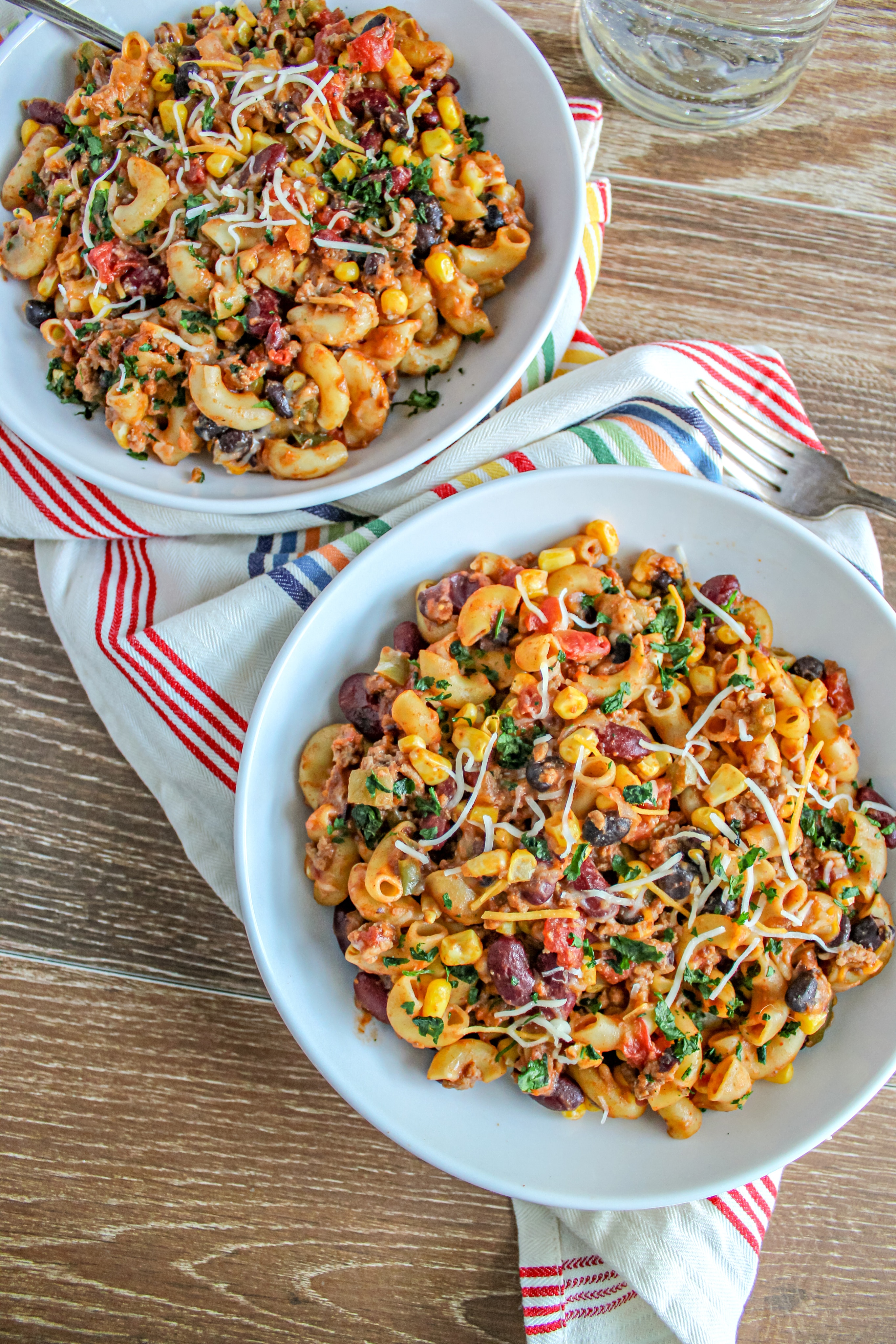 Two white bowls of instant pot taco pasta on a wood board. 