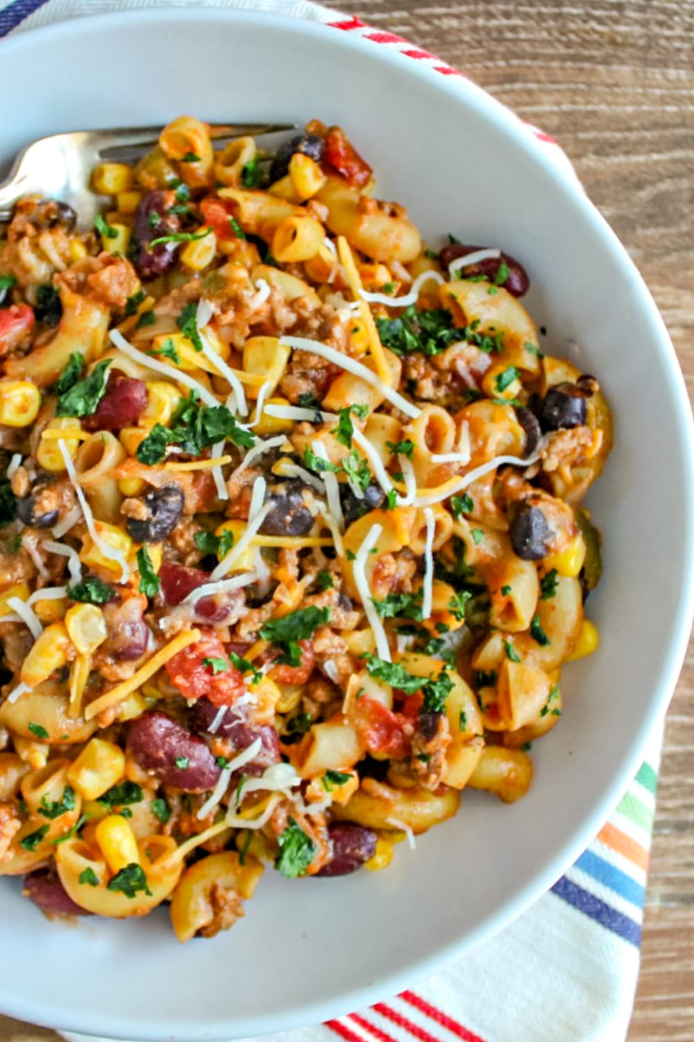 Taco Pasta made in the instant pot in a white bowl garnished with cilantro and shredded cheese. 