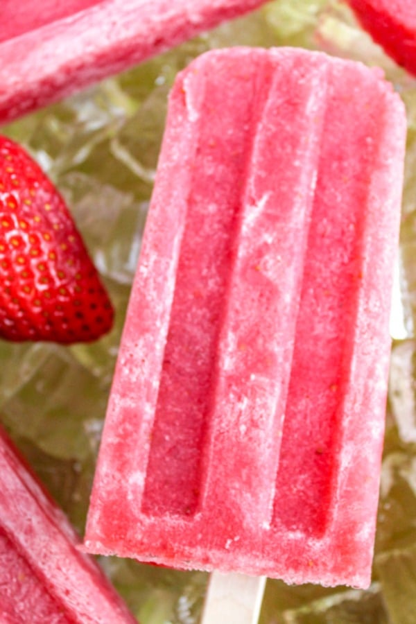 Strawberry Daiquiri Popsicle on wooden stick laying on a bed of ice   