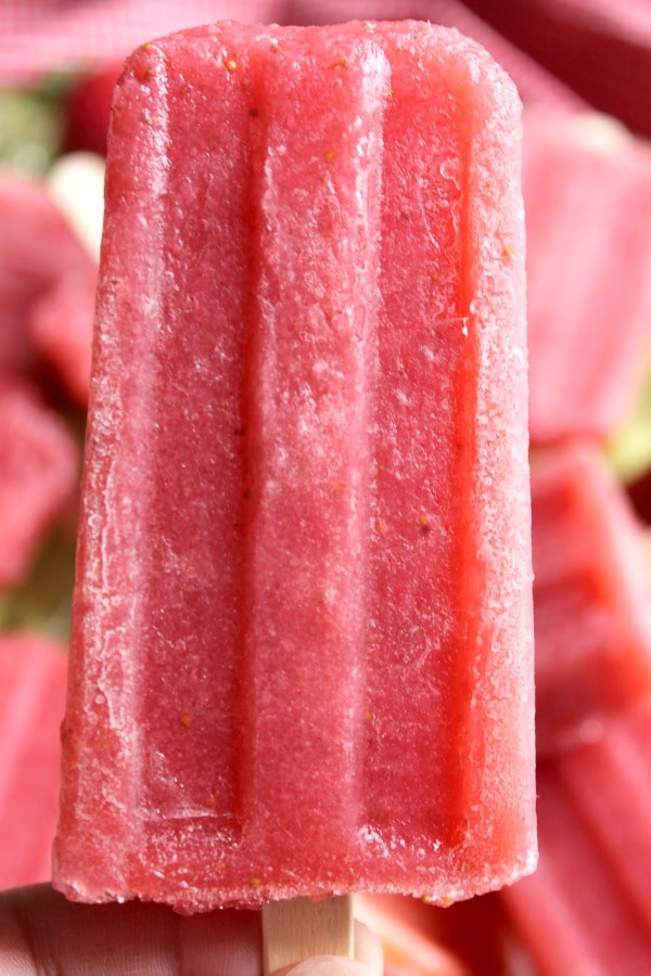 Woman's hand holding a Fresh Strawberry Daiquiri Popsicle on wooden stick  