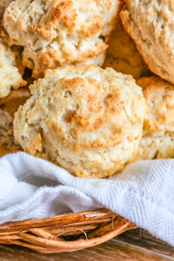 Easy Drop Biscuits in a straw basket lined with white towel on wooden cutting board 