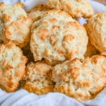 Easy Drop Biscuits in a straw basket lined with white towel on wooden cutting board