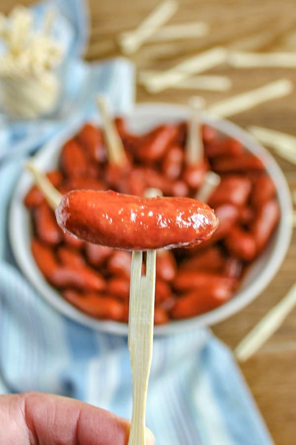 Sweet and Spicy Little Smokies Appetizer on toothpick on front of a bowl of smokies