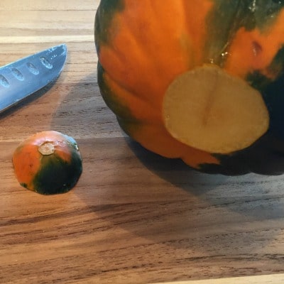 Acorn squash on cutting board shown with end sliced off 