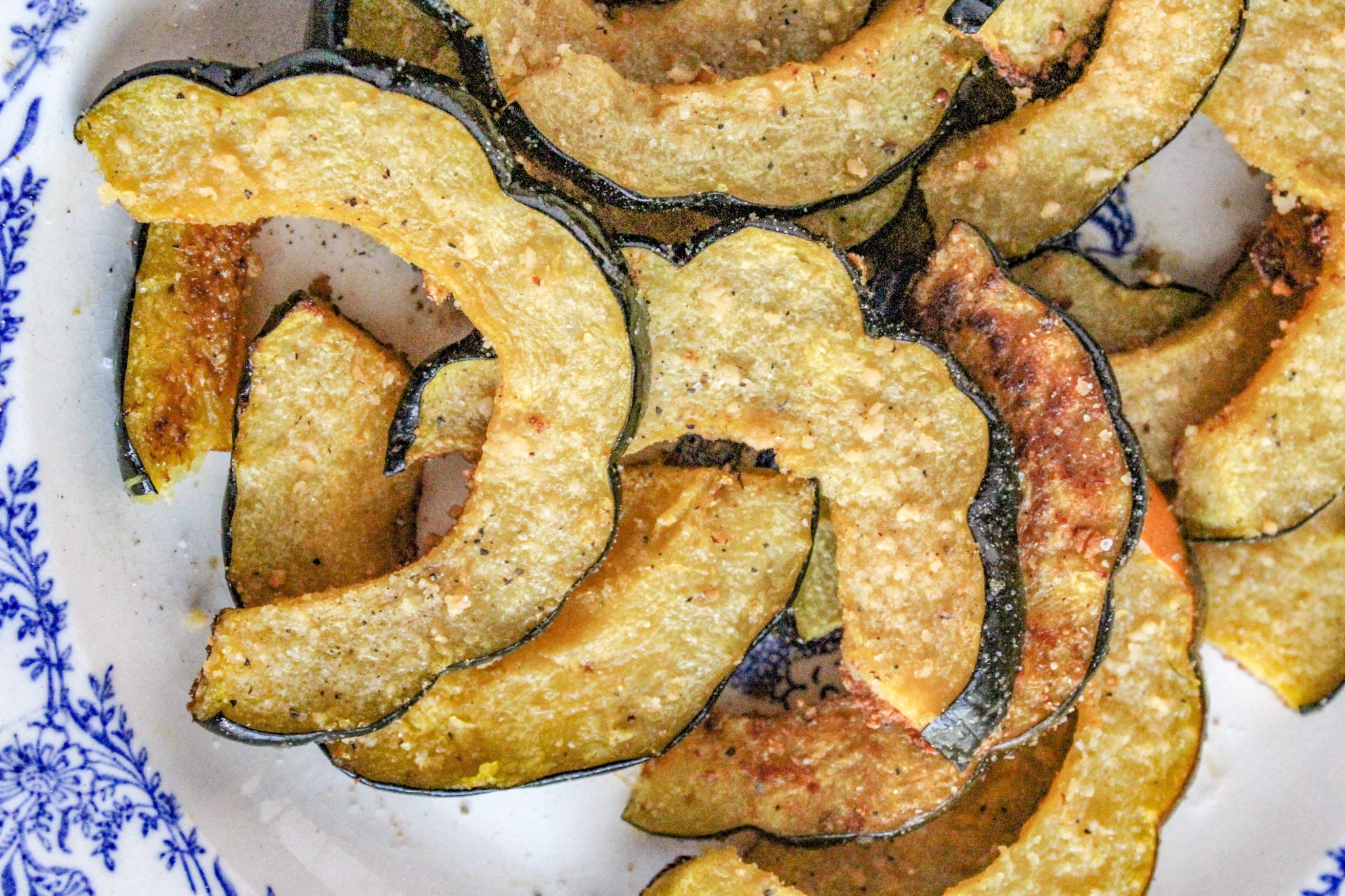 Oven Roasted Parmesan Acorn Squash on a platter with blue and white boarder. 