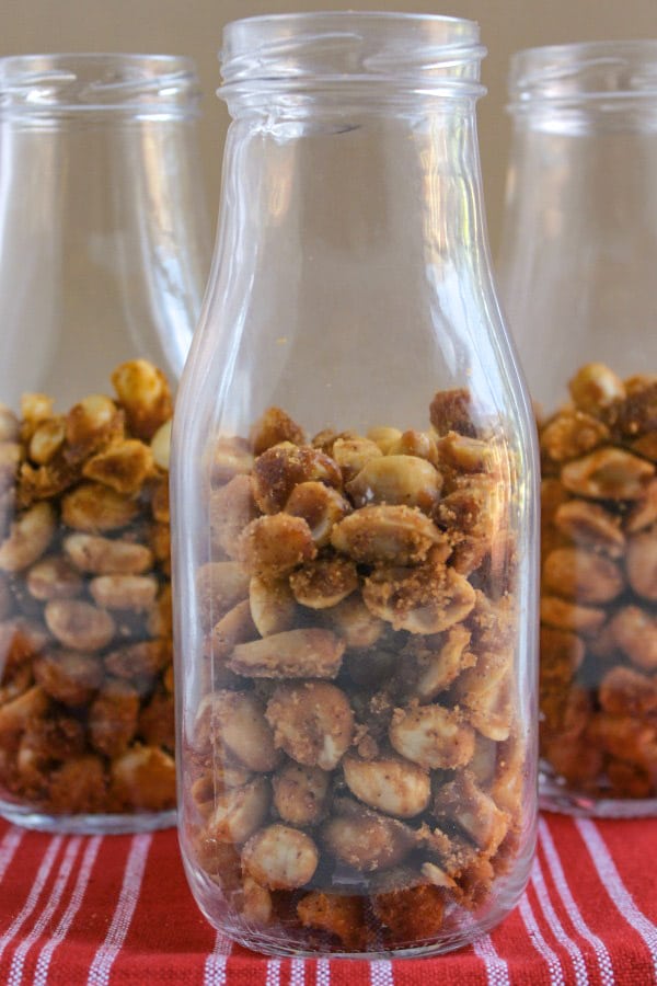 slow cooker candied peanuts in three glass bottles 