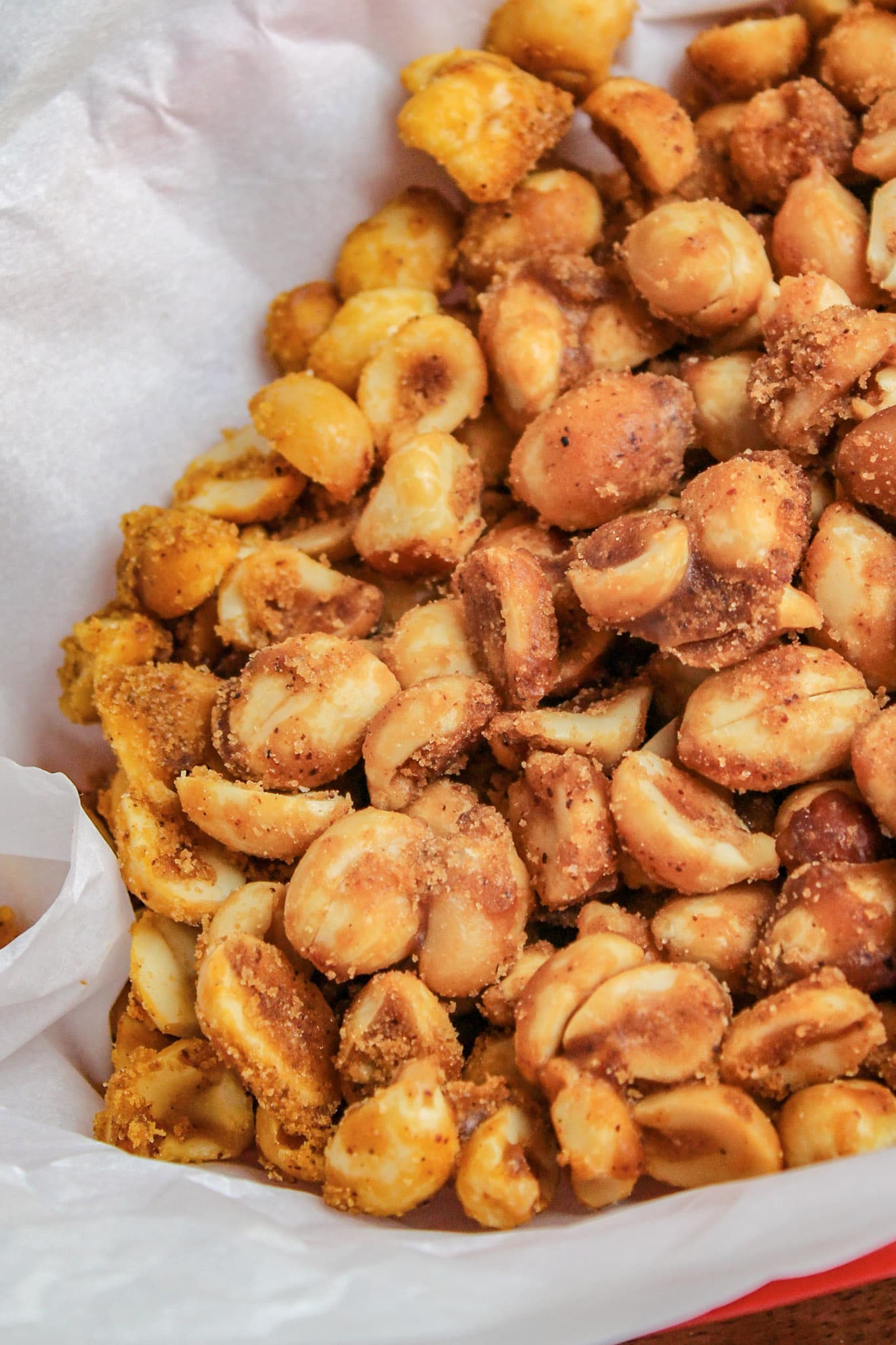 Slow Cooker Sweet and Spicy Peanuts in a red basket with white parchment paper 