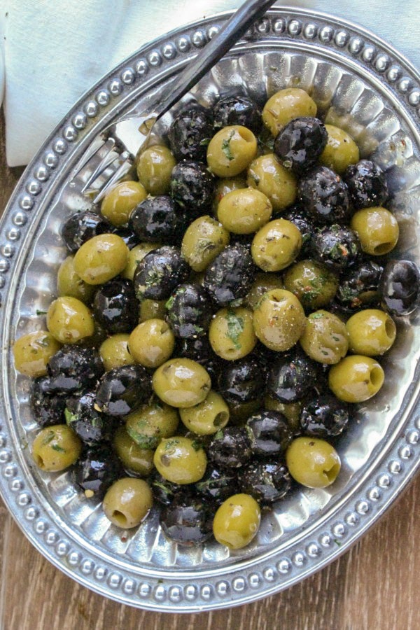 Garlic and Herb Marinated Olives on a pewter platter with an hors d'oeuvre fork 