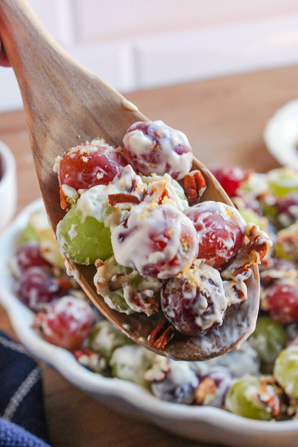 A single wooden spoon holds a scoop of grape salad.