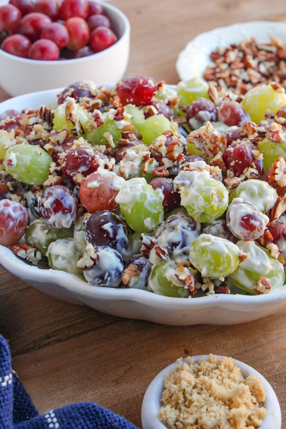 Grape salad in a white bowl garnished with chopped pecans.
