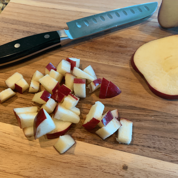 Diced red apples on a woodcutting board with chef's knife. 
