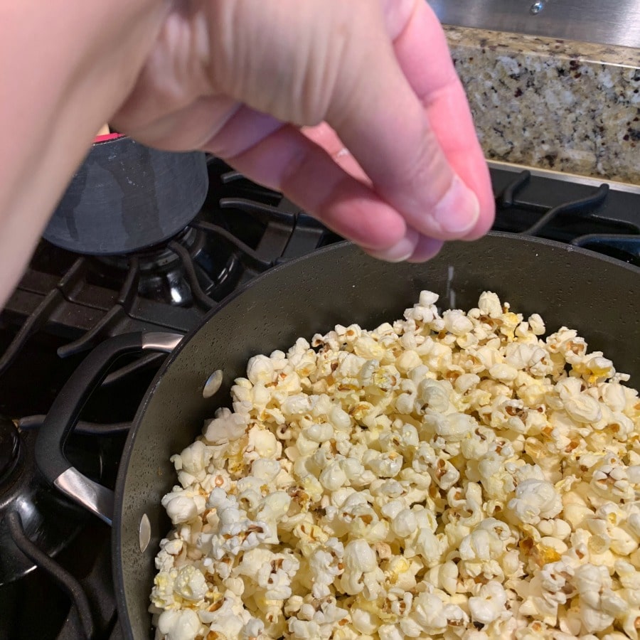 Photo of stovetop popcorn being salted. 