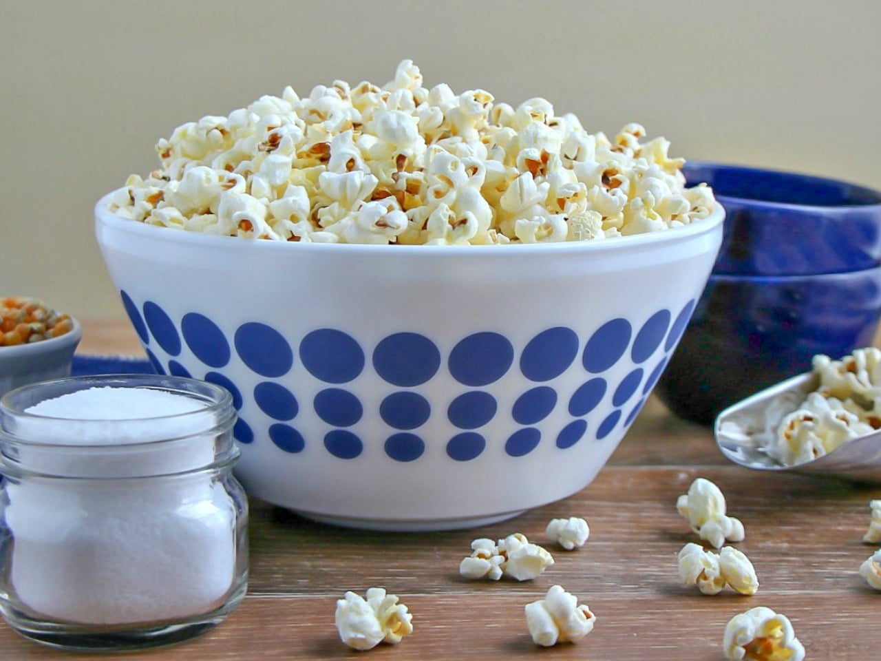 Stovetop Popcorn piled high in a white bowl with blue polka dots. 