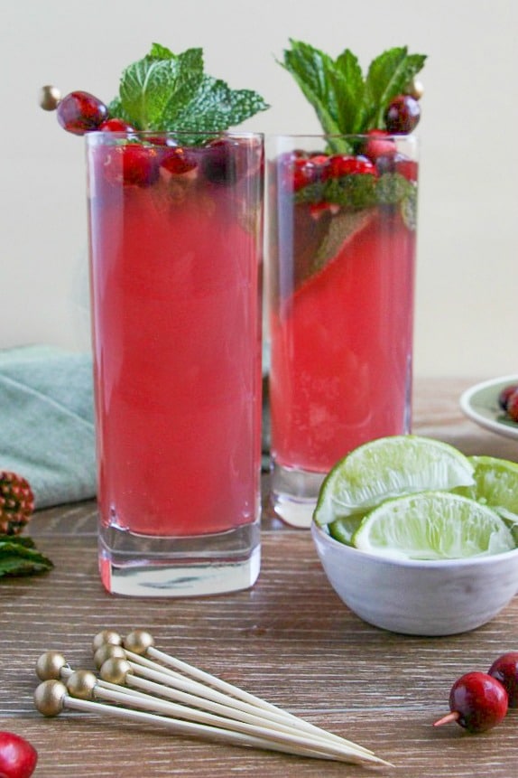 Two glasses of Cranberry Mojito garnished with fresh mint and cranberries. 