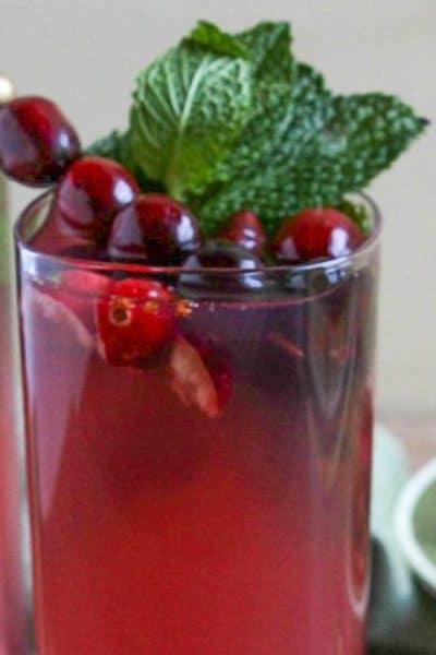 Cranberry Mojito in a square glass garnished with fresh mint and cranberries