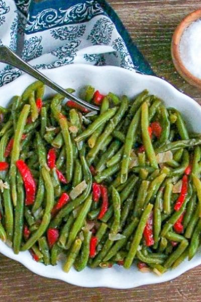 Green Beans with Roasted Red Peppers in a white serving bowl with vintage spoon and salt cellar.