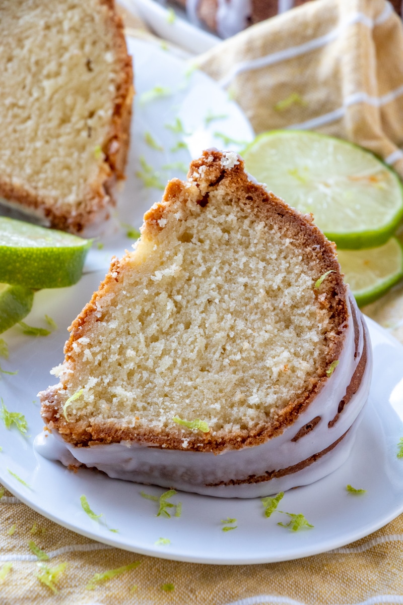 Two slices of 7 Up cake on white plates garnished with fresh lime zest. 