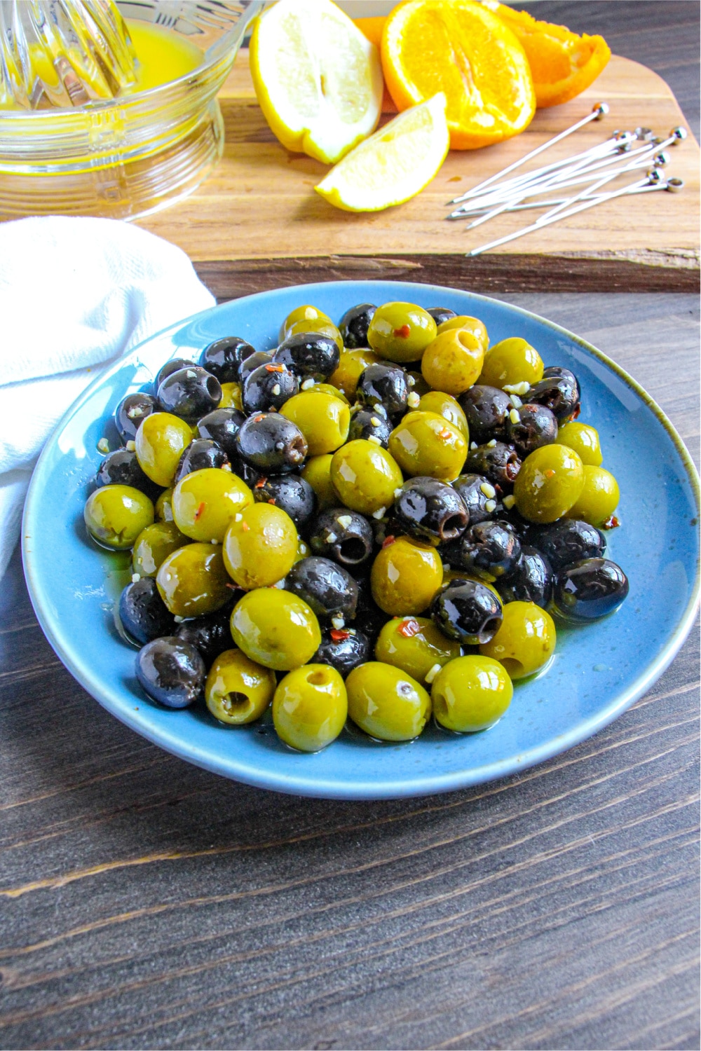 Green and black Citrus Marinated Olives in a blue bowl. 