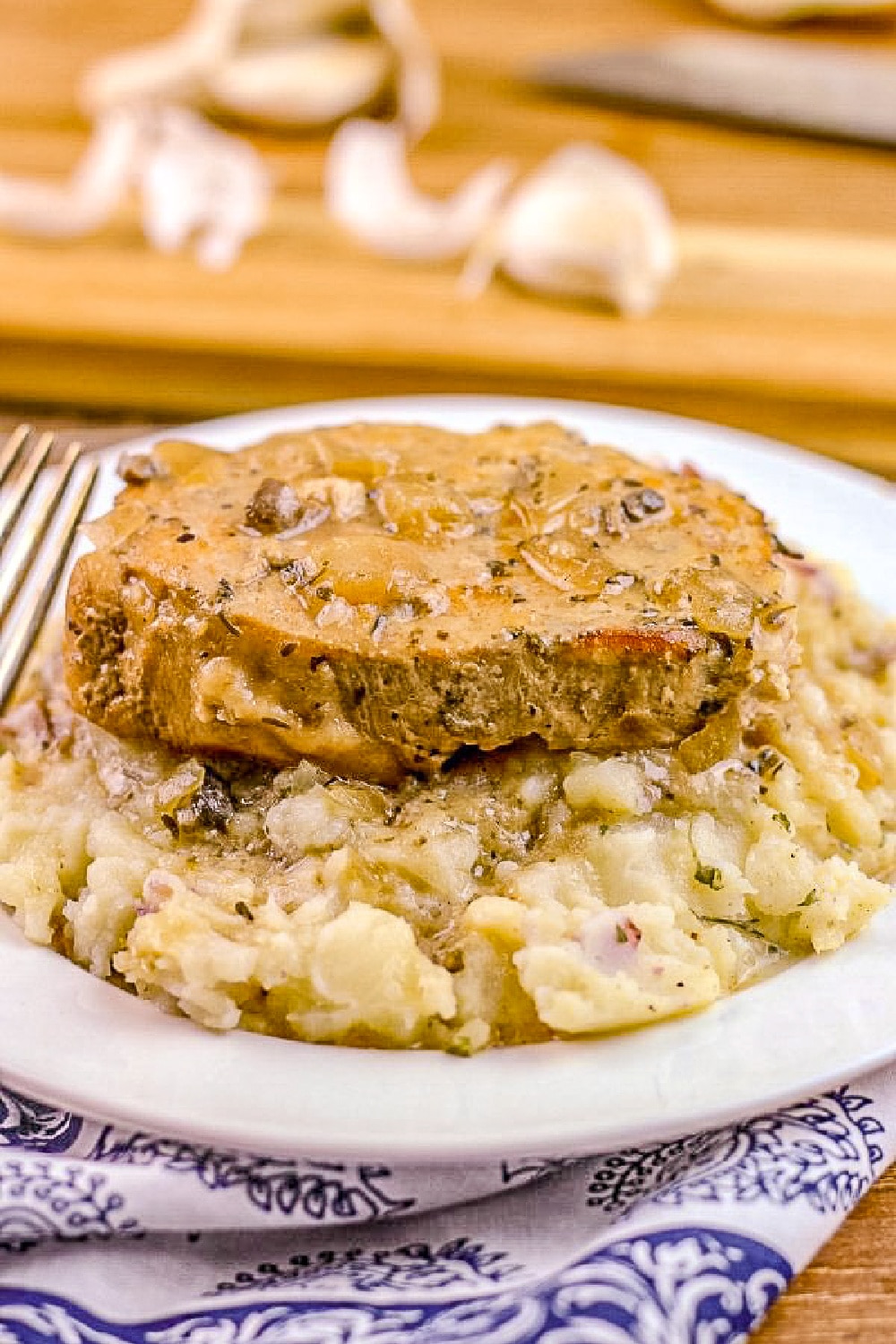 Pork Chop smothered in gravy sits on a bed of mashed potatoes.