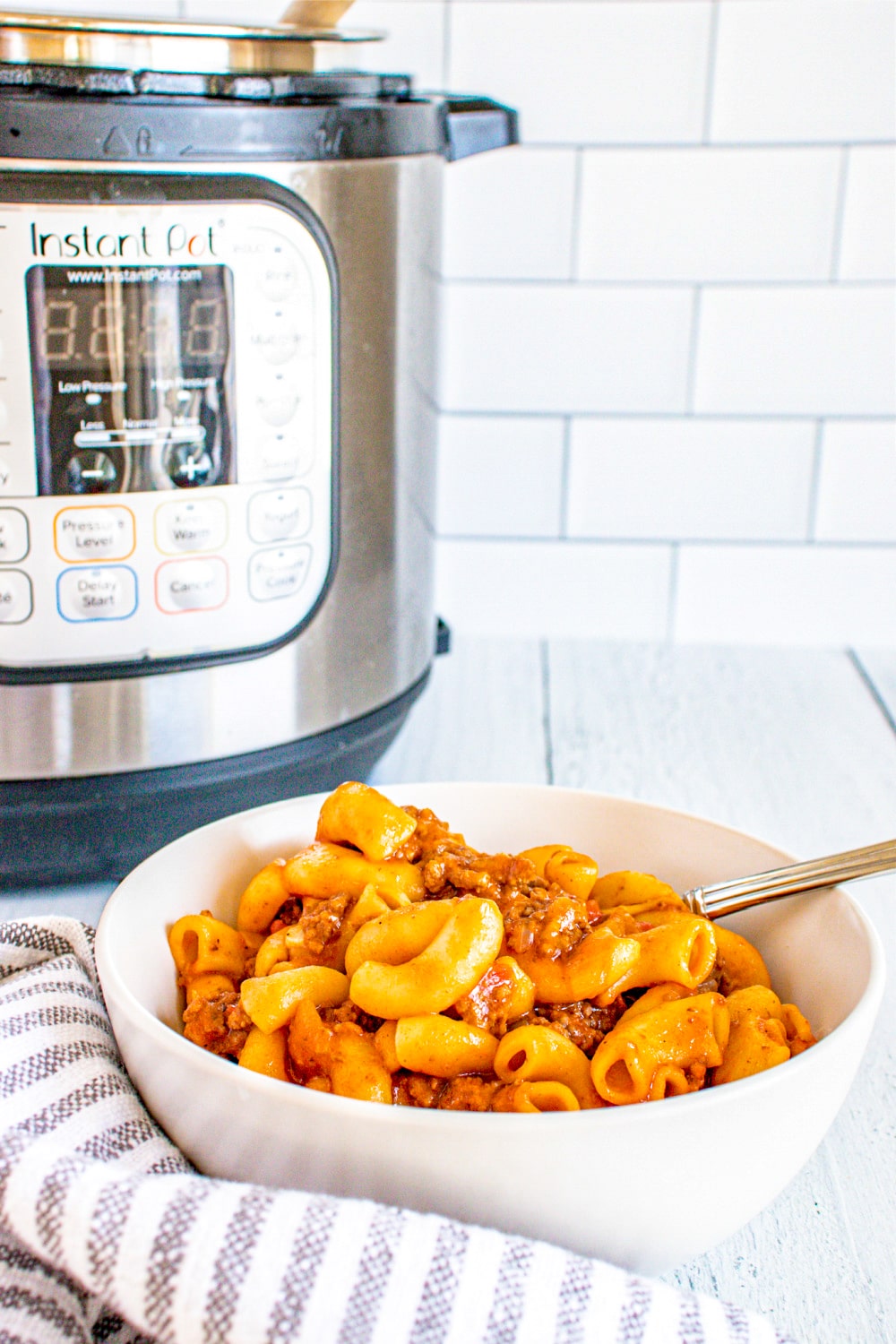Instant Pot Goulash in a white bowl shown with Instant Pot 