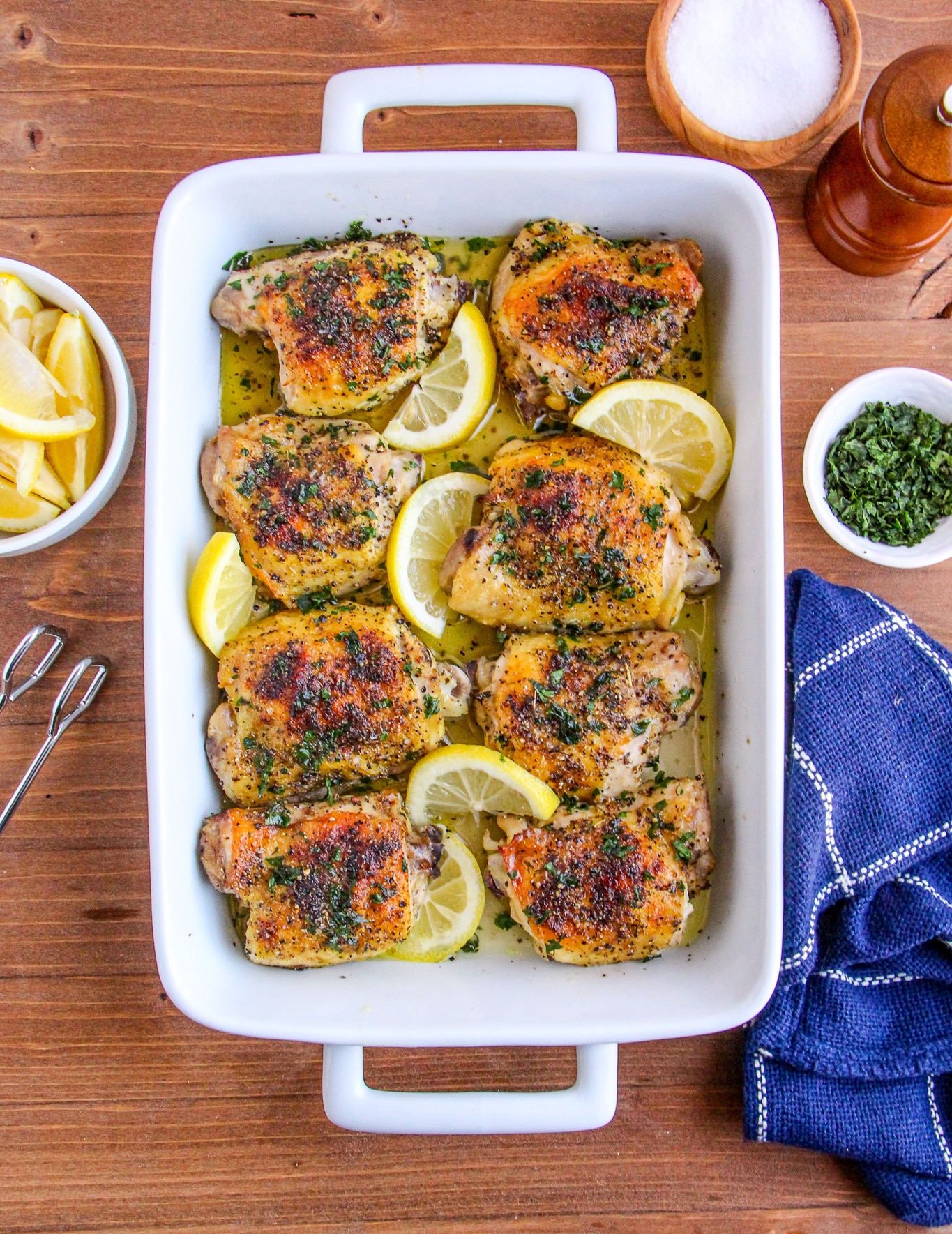 Lemon Pepper Chicken Thighs in a white baking dish garnished with lemon slices.