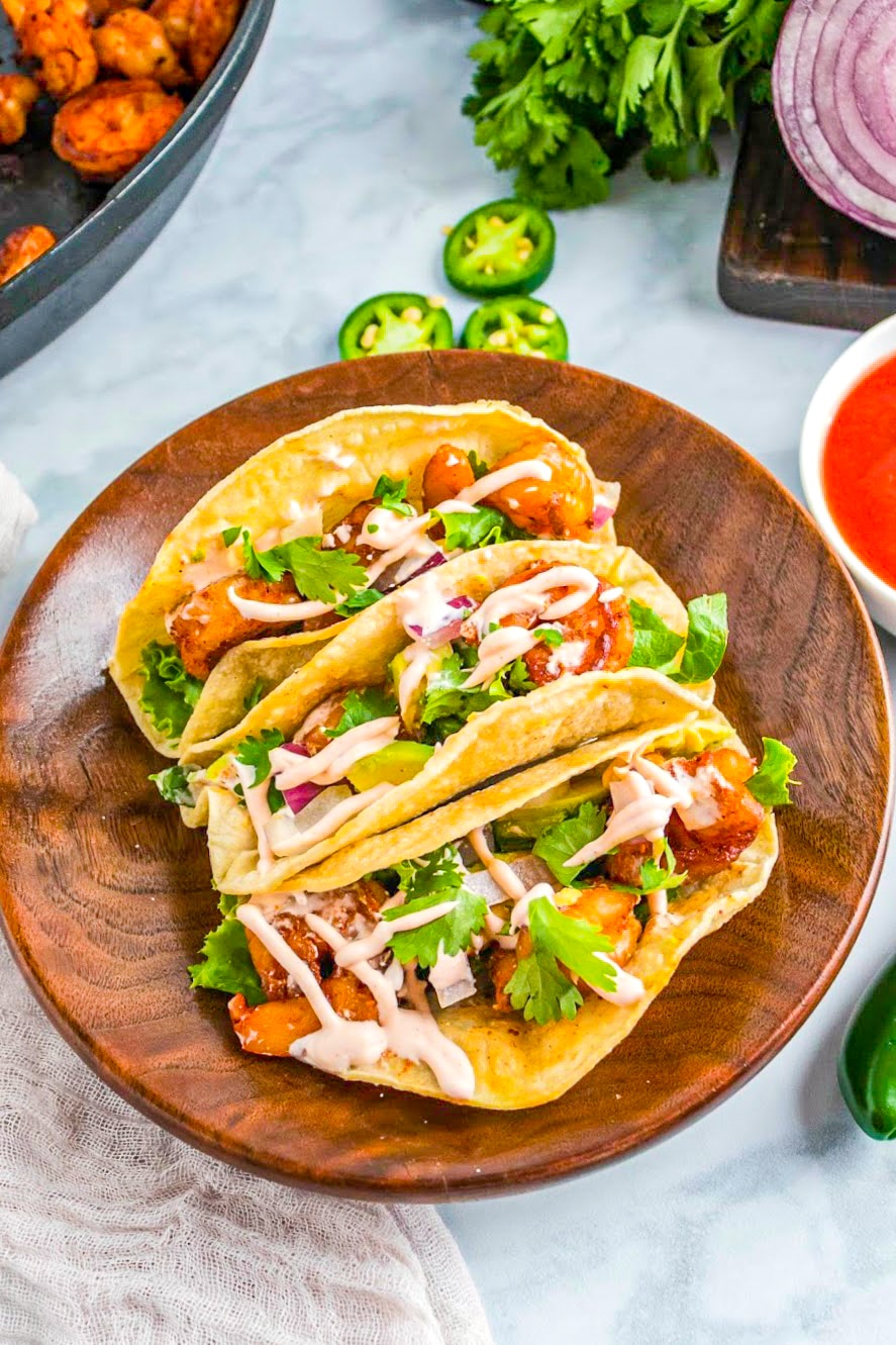 Three Chipotle Shrimp Tacos on a wood tray.