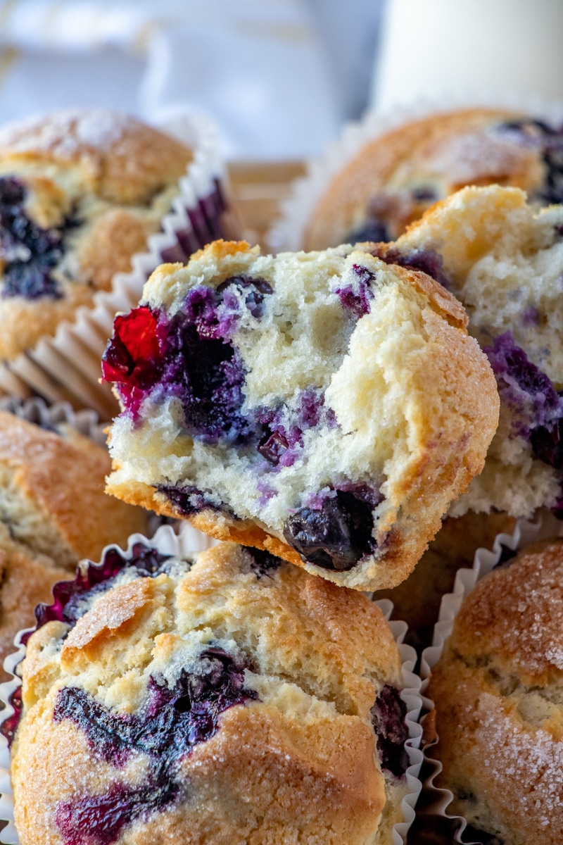 A muffin with a bite missing shoring the juicy berries on the inside