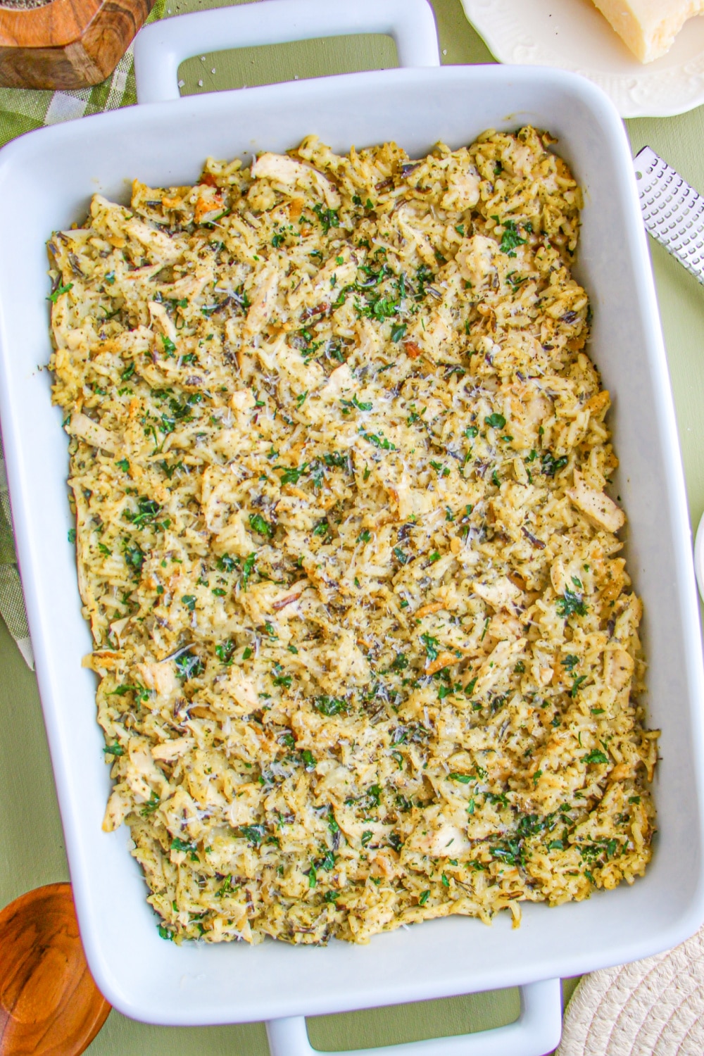 A white baking dish with Chicken and Wild Rice Casserole on a green background. 