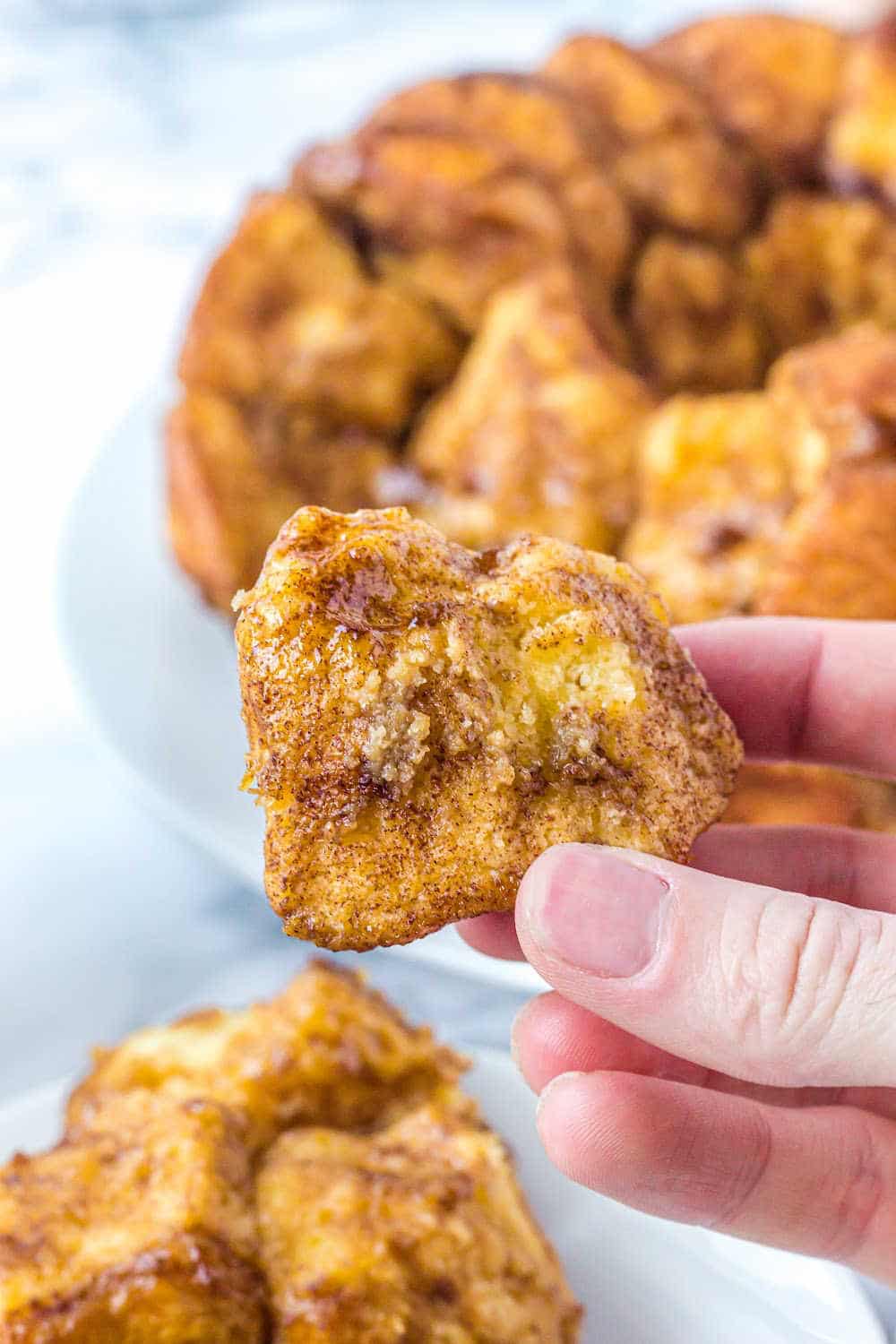 A woman's hand holding a piece of Monkey Bread. 