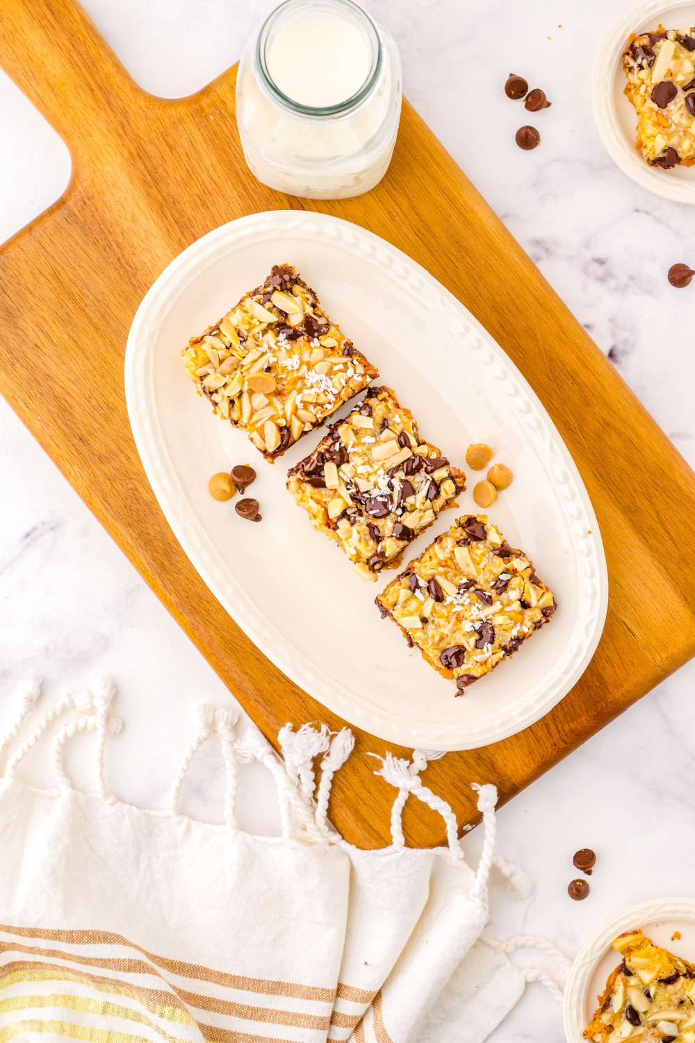 Three cookie bars on a white dessert plate sitting on a wood cutting board.