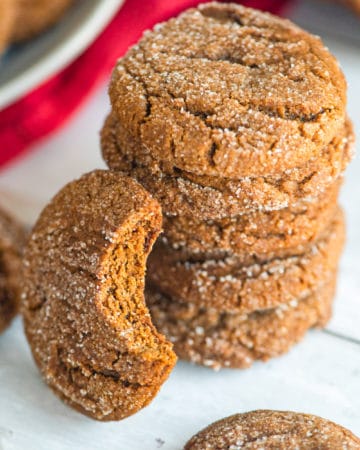 A stack of gingersnap cookies next to a red dish towel.