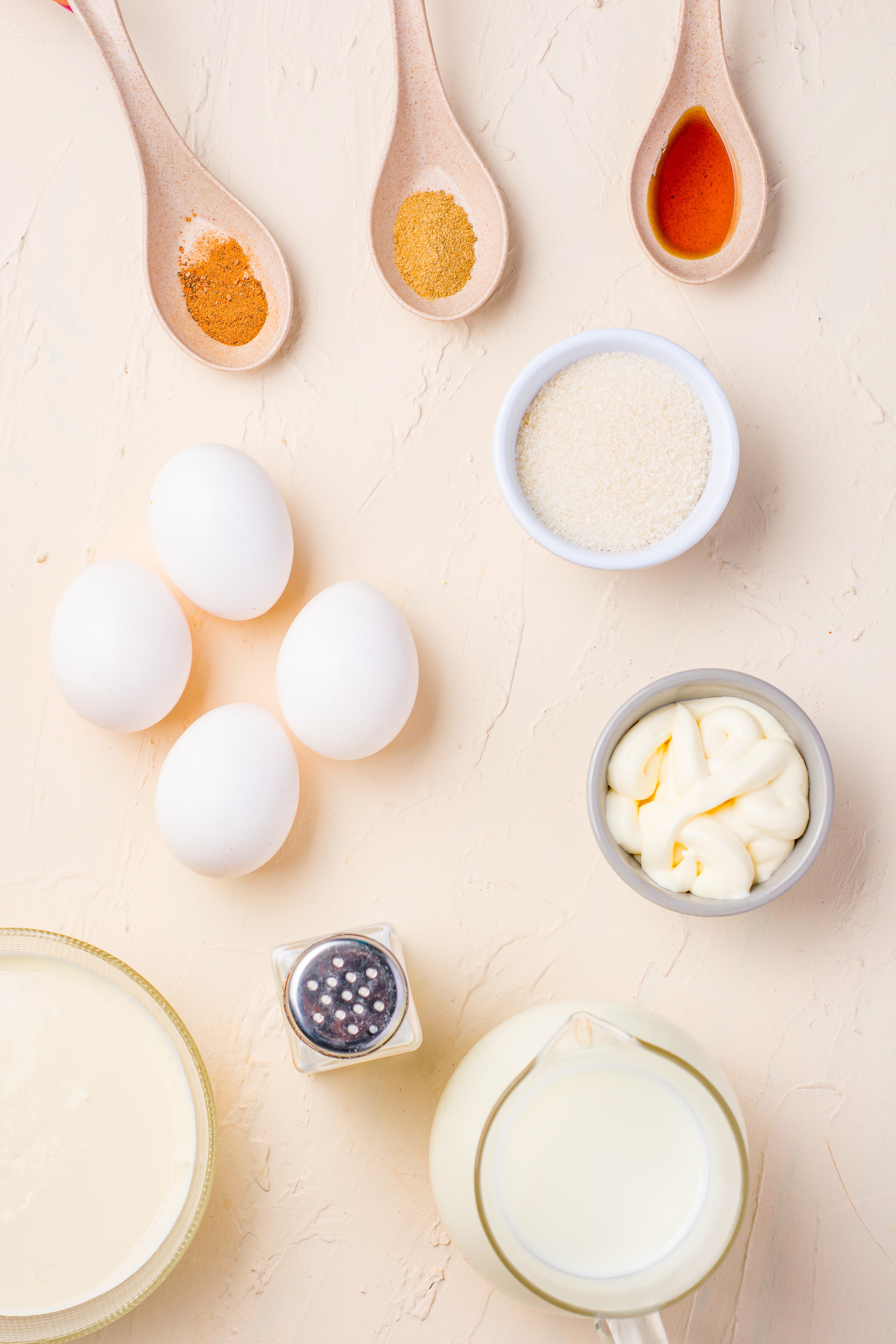 Measured ingredients need to make egg nog in bowls.