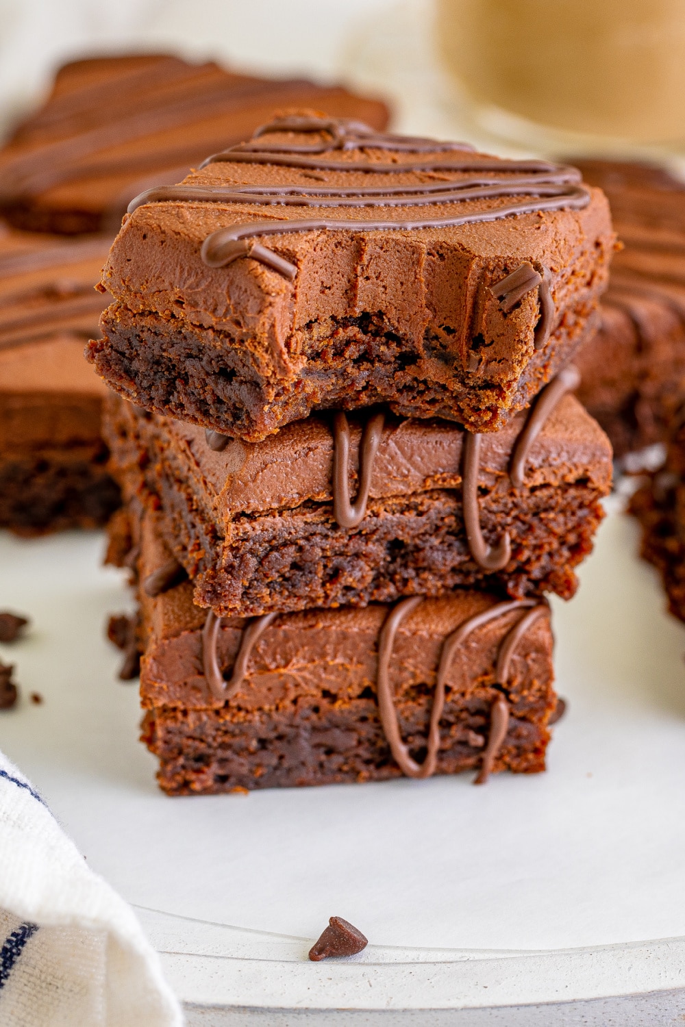 Three brownies stacked on a white platter. 