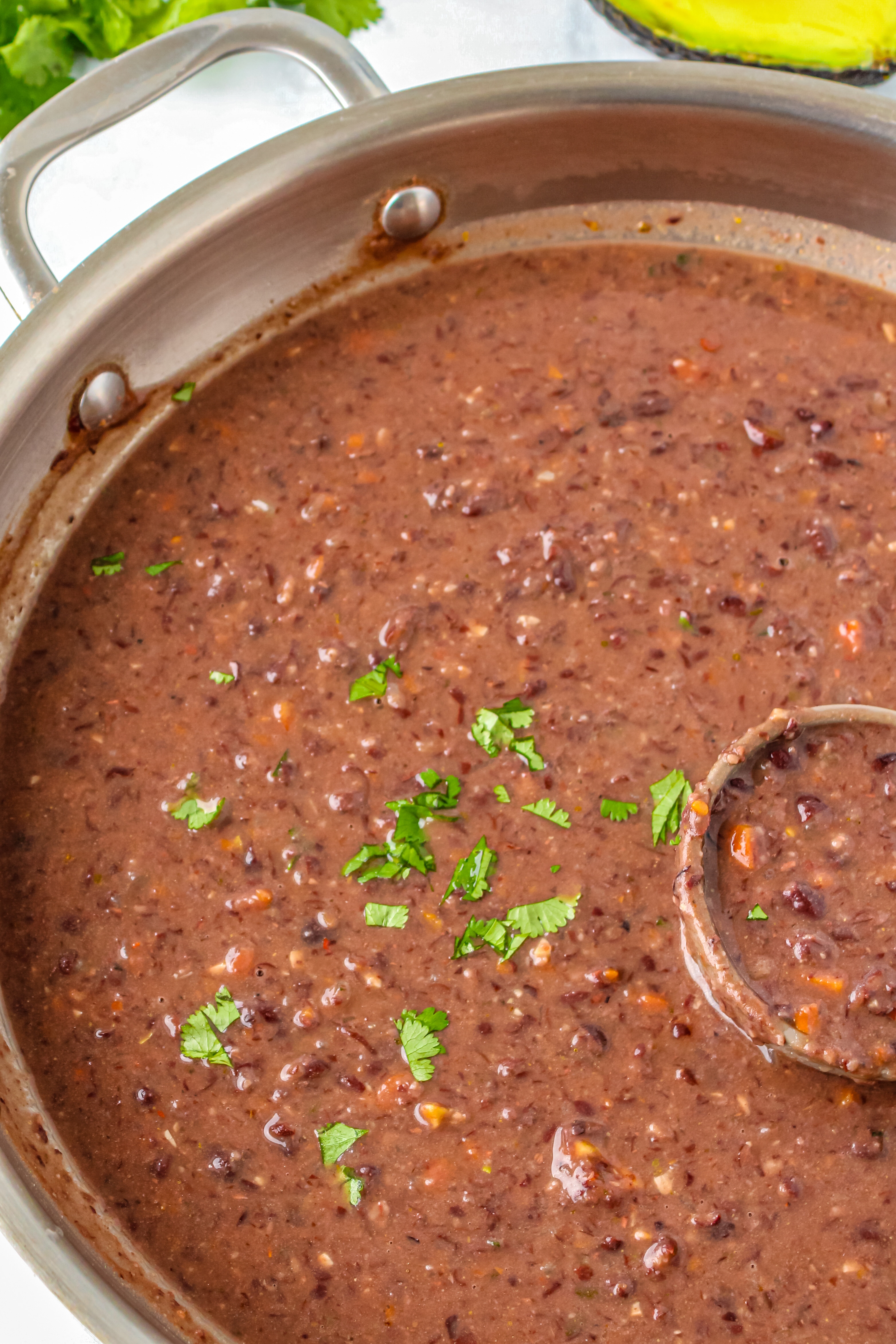A soup pot of prepared black bean soup with a sprinkle of fresh chopped cilantro.