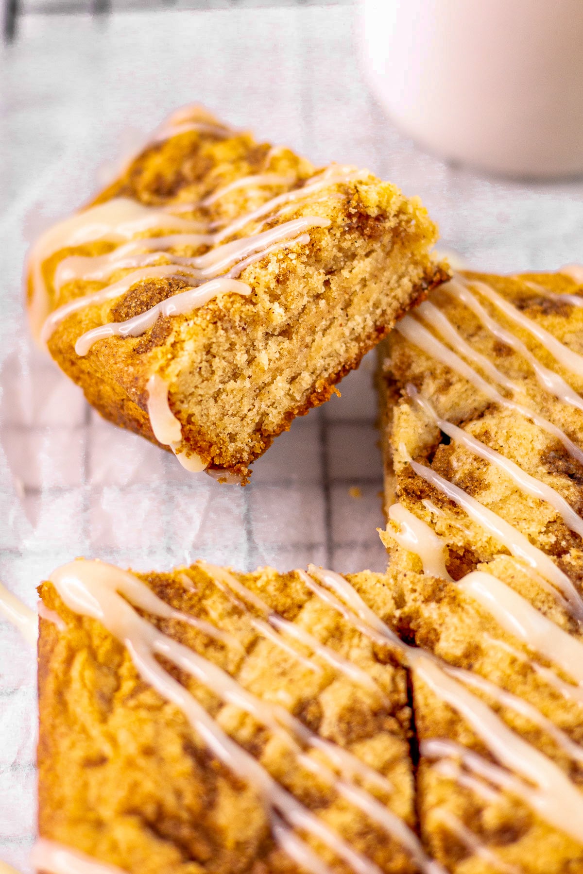 Squares of blondies drizzled with cream cheese frosting sitting on a cooling rack.
