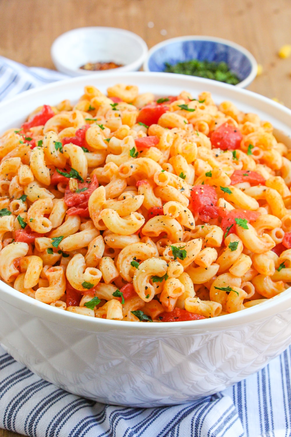 Macaroni and Tomatoes in a white bowl garnished with parsley.