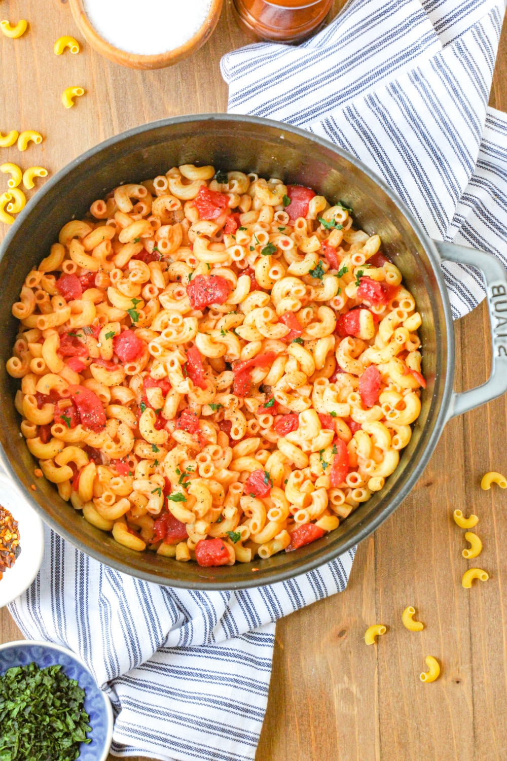 Macaroni and Tomatoes in a large pot sitting on blue and white dish towel. 