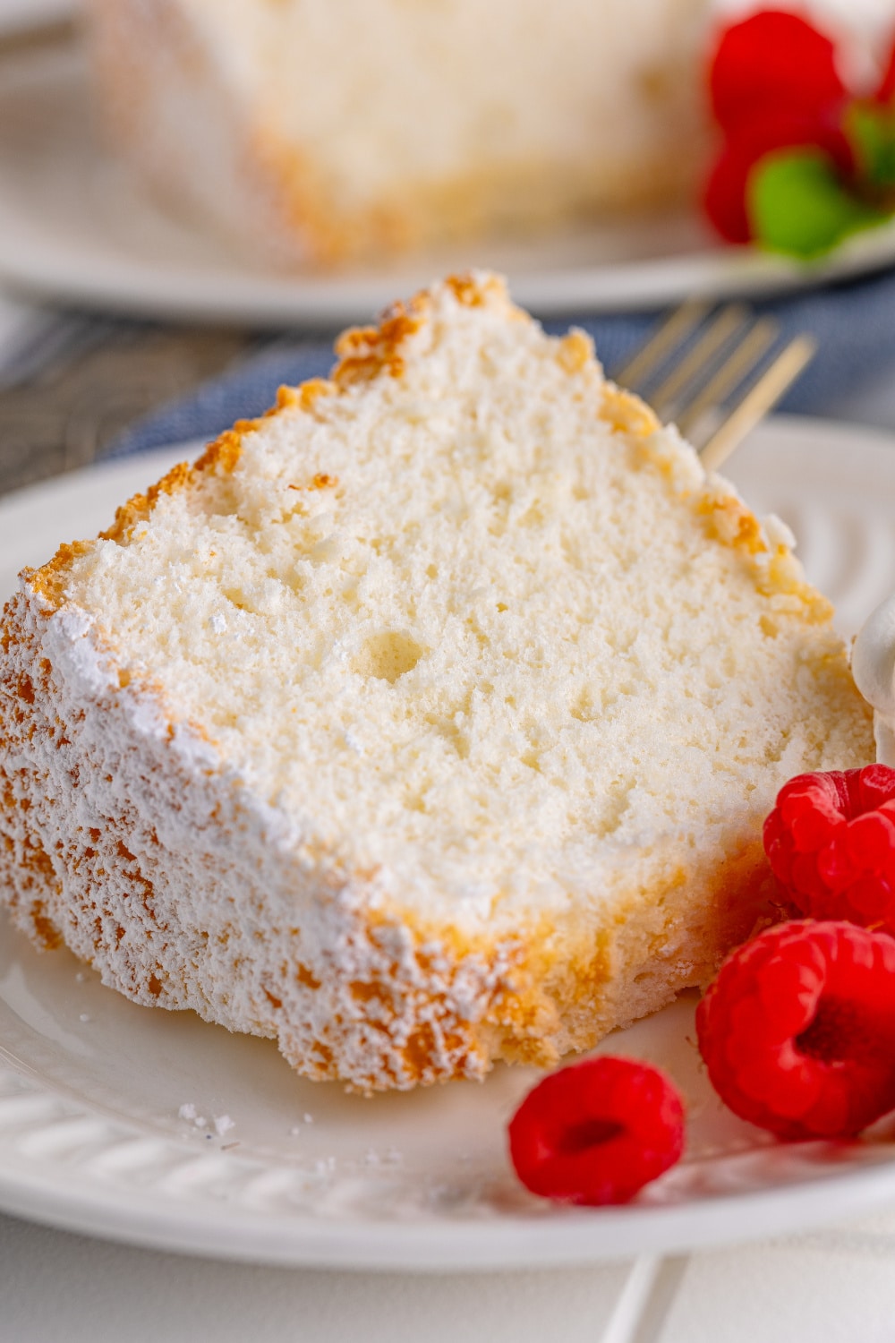 A thick slice of Angel Food Cake with red berries on a white dessert plate.