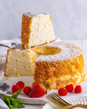 A slice of Angel Food Cake on a cake server near the remainder of the cake.