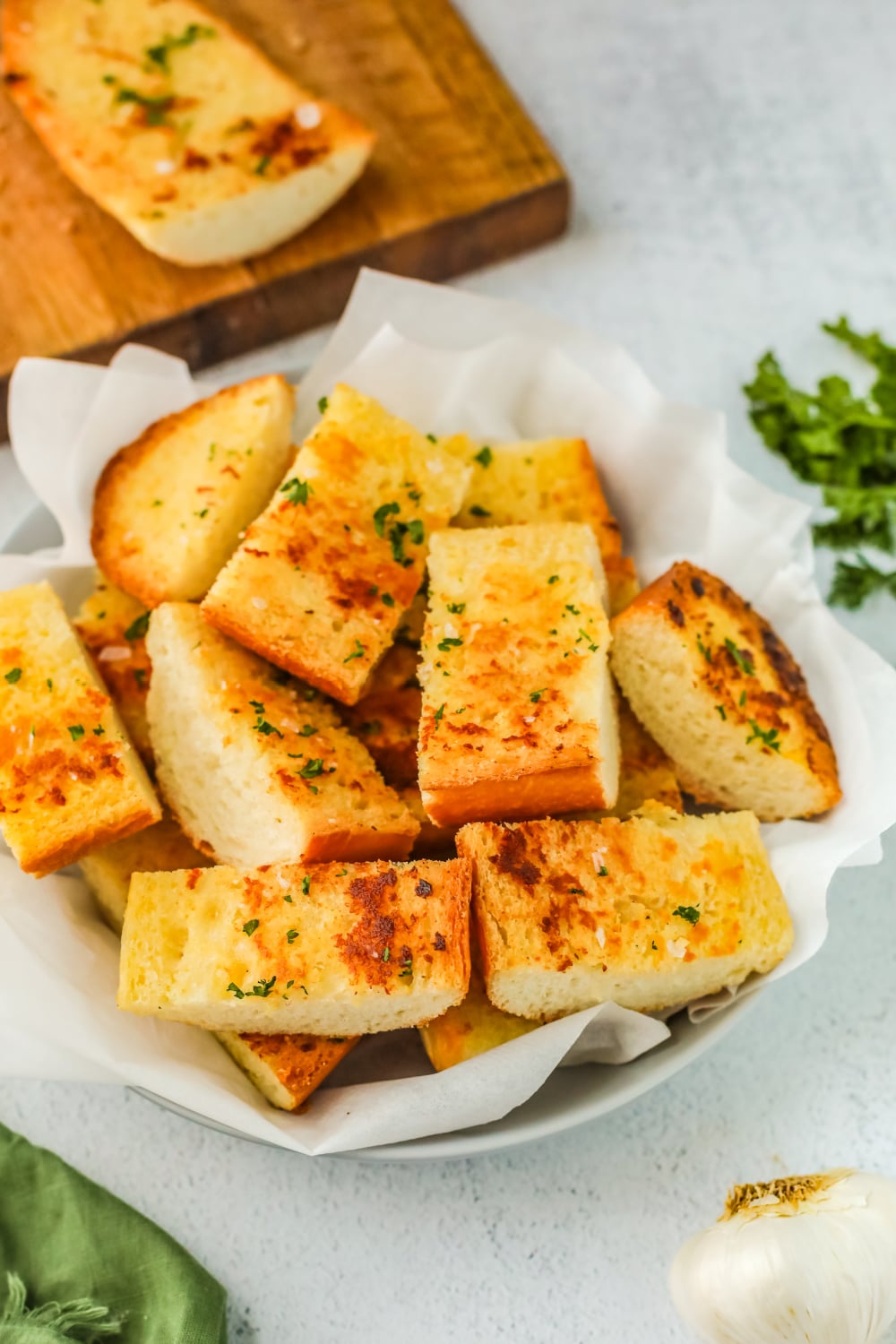 Slices of Easy Garlic Bread piled in a basket on a white background.