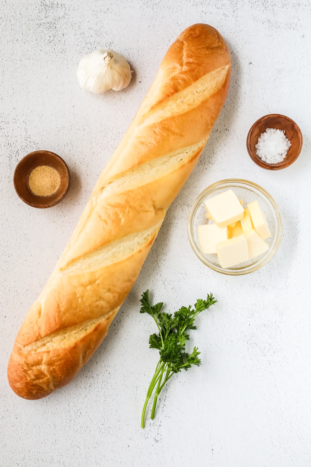 A loaf of Italian bread surrounded by measured ingredients needed for this recipe.