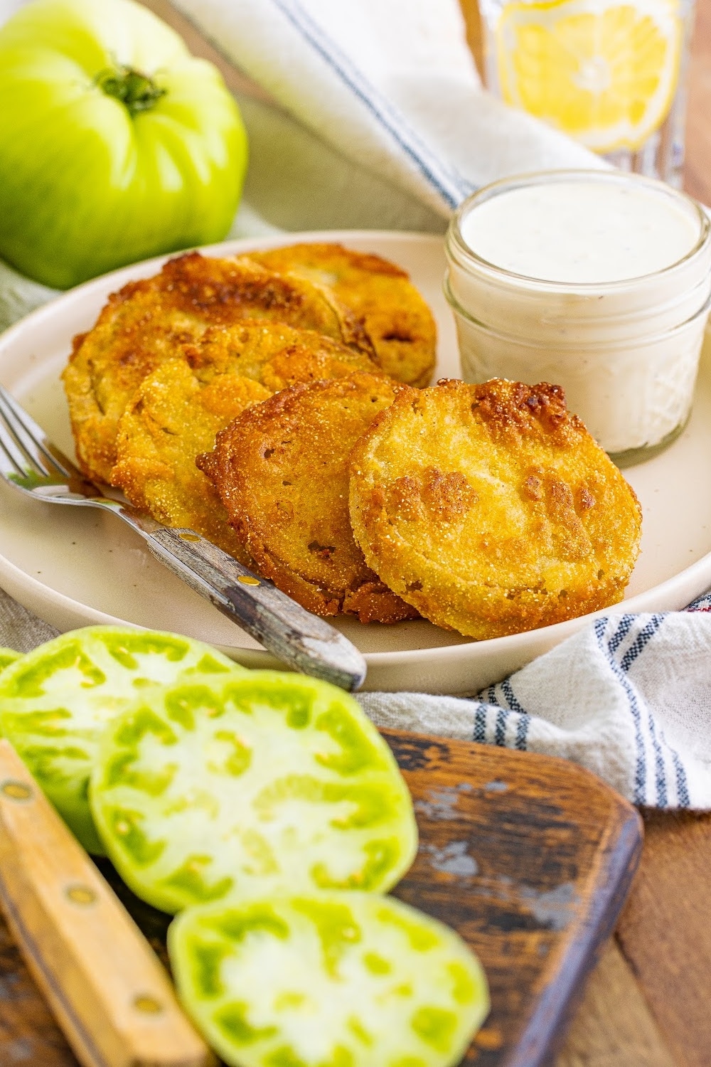Fried Green Tomatoes on a white plate with ranch in a clear jar for dipping.