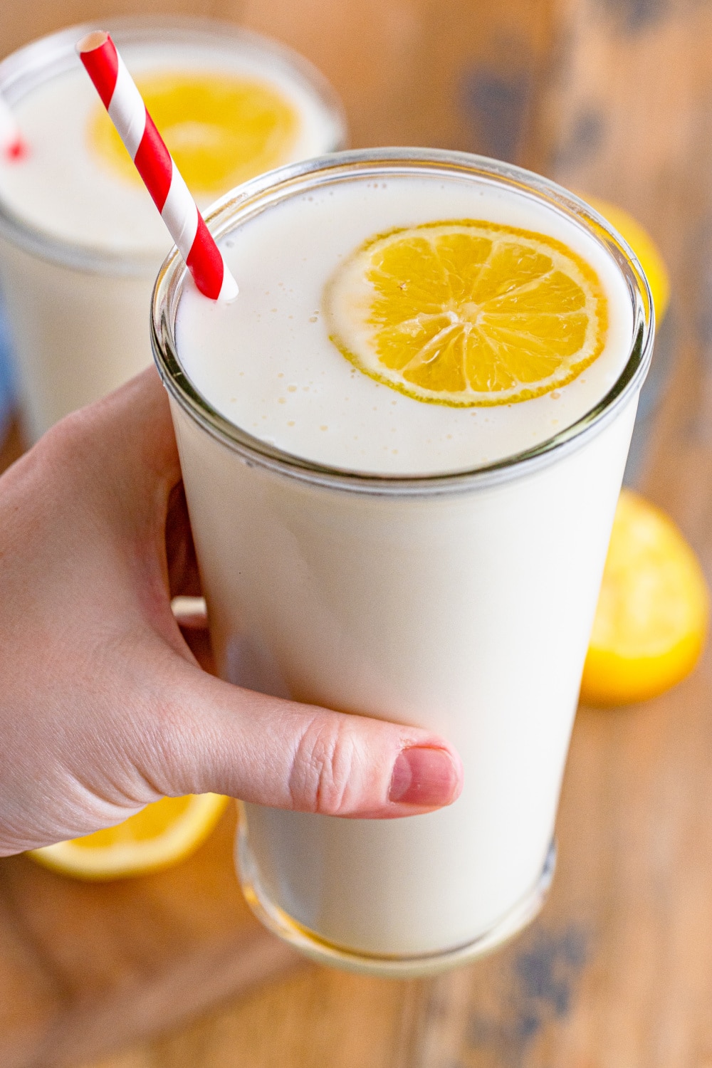 A woman's hand holding a glass of frosted lemonade.