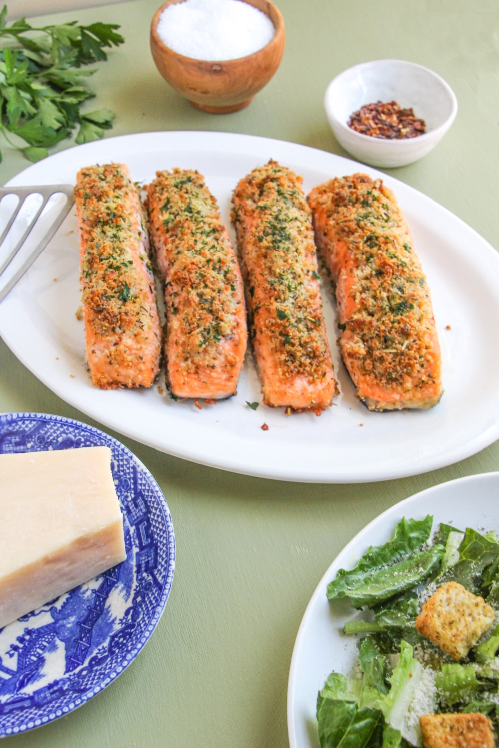 Salmon fillets on a white platter garnished with parsley.